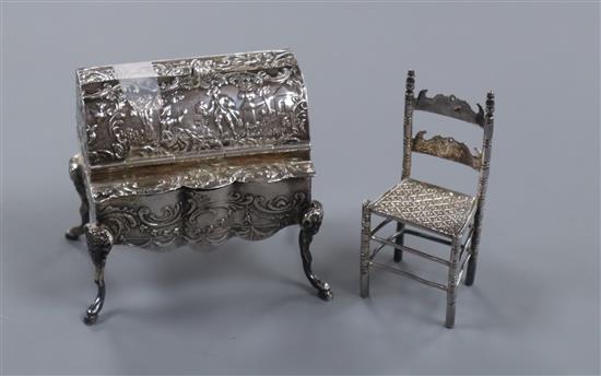 A miniature silver bureau with pseudo-Hanau marks, import marks for Samuel Boyce Landeck and a miniature white metal chair